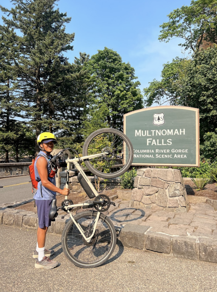 E bike rider in front of Multnomah Falls Columbia River Gorge National Scenic Area sign